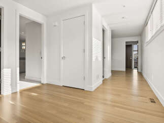 Step into this bright and airy hallway, featuring gleaming hardwood floors that reflect the natural light streaming through the blinds.