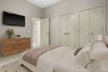 This modern bedroom features a sleek Samsung TV mounted above a stylish wooden dresser, perfect for entertainment.