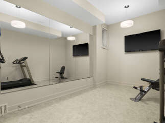 This home gym features a spacious layout with a large mirror, a treadmill, and a weight bench, perfect for your fitness routine.