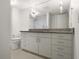 This modern bathroom features a sleek vanity with ample storage and a granite countertop, complemented by a stylish faucet.