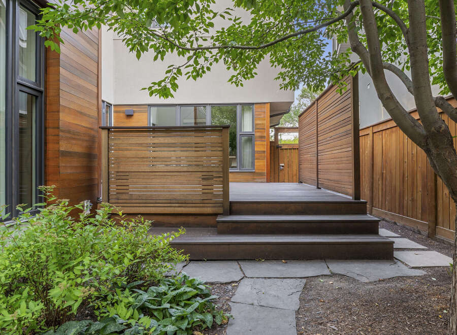 Experience modern outdoor living with this beautifully designed backyard featuring a spacious wooden deck and a privacy screen.