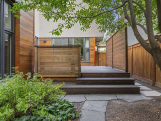 Experience modern outdoor living with this beautifully designed backyard featuring a spacious wooden deck and a privacy screen.