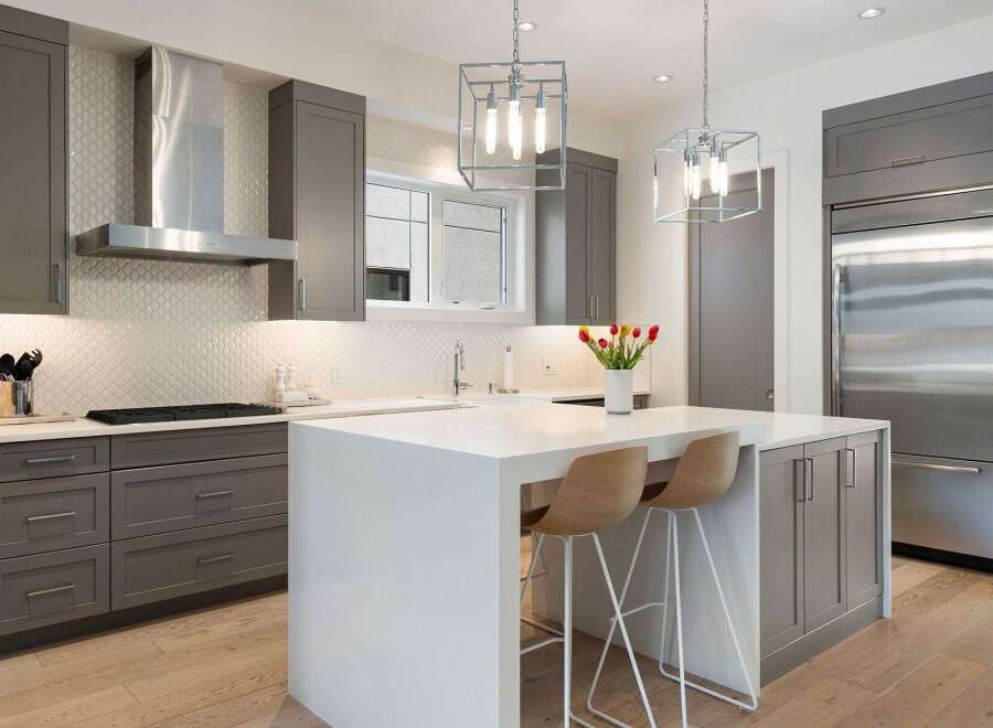Experience modern luxury in this stunning kitchen, featuring sleek grey cabinetry and a gleaming stainless steel range hood.