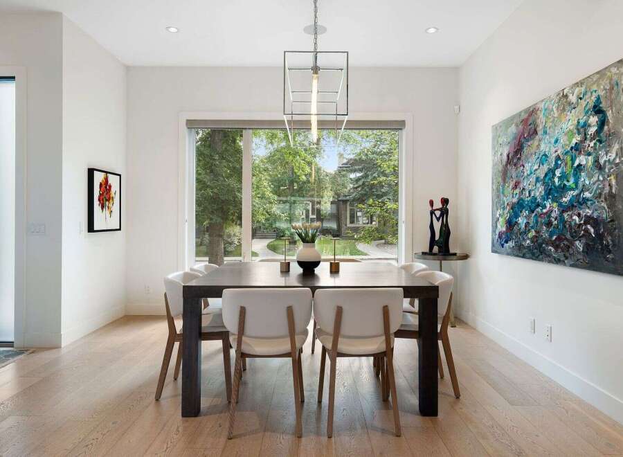 Experience elegant dining in this beautifully appointed space, featuring a large dark wood table surrounded by modern white chairs.