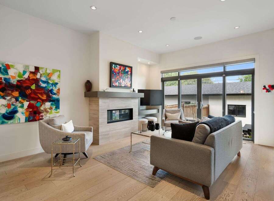 Experience modern living in this stunning living room, featuring a sleek fireplace and large glass doors that open to a private outdoor space.