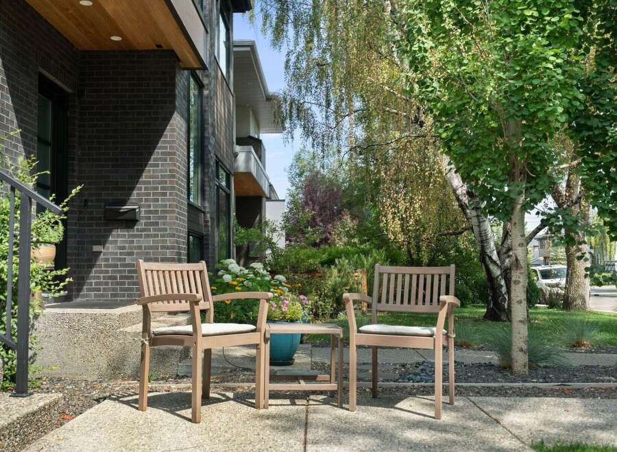 Enjoy your morning coffee on the charming front porch, complete with two wooden chairs and a small table, perfect for outdoor relaxation.
