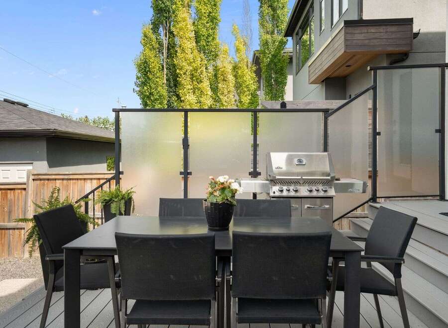 Enjoy outdoor living with this modern patio featuring a sleek dining set and a high-end grill, perfect for entertaining.