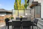 Enjoy outdoor living with this modern patio featuring a sleek dining set and a high-end grill, perfect for entertaining.