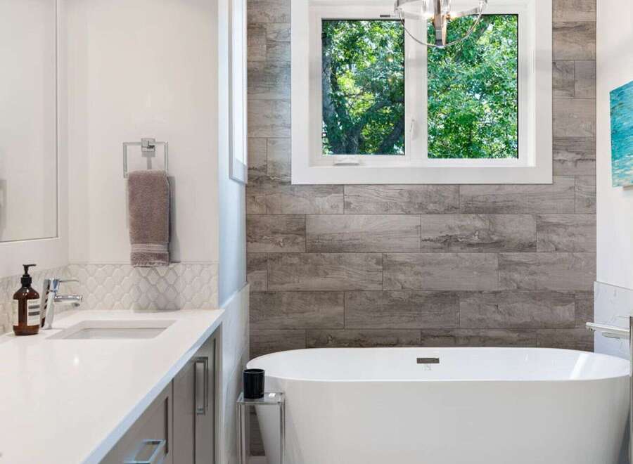 Experience modern luxury in this stunning bathroom featuring a freestanding soaking tub and a sleek vanity with a vessel sink.