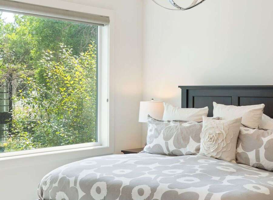 Experience serene living with this beautifully appointed bedroom, featuring a large window that floods the space with natural light and offers picturesque views of lush greenery.