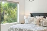 Experience serene living with this beautifully appointed bedroom, featuring a large window that floods the space with natural light and offers picturesque views of lush greenery.
