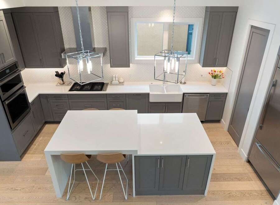 Experience modern luxury in this stunning kitchen, featuring sleek grey cabinetry and a spacious white island perfect for entertaining.
