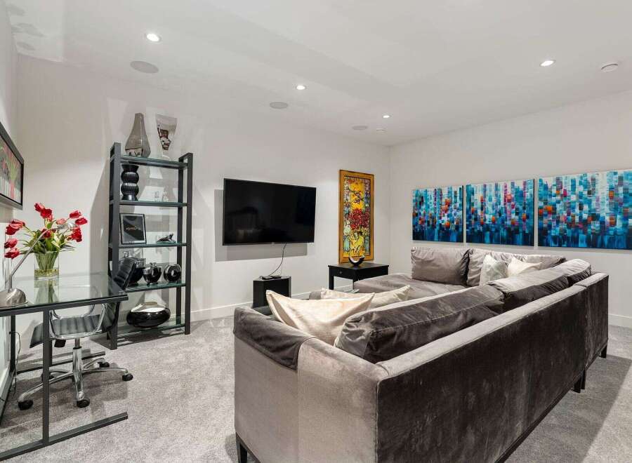 This modern living room features a sleek glass desk with a comfortable office chair, perfect for a home office setup.