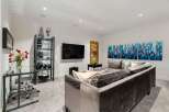 This modern living room features a sleek glass desk with a comfortable office chair, perfect for a home office setup.