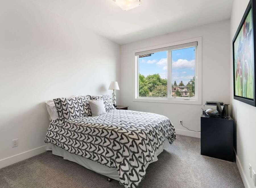This charming bedroom features a comfortable queen-size bed adorned with a stylish heart-patterned duvet and matching pillows.