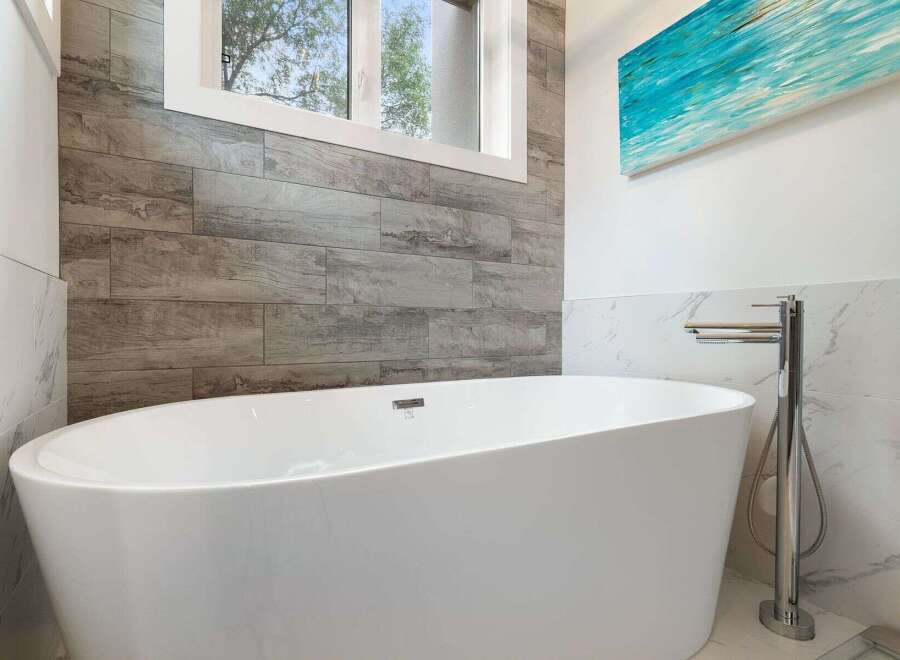 Indulge in luxury with this stunning freestanding bathtub, perfectly complemented by elegant wood-look tile and marble accents.
