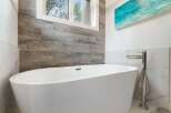 Indulge in luxury with this stunning freestanding bathtub, perfectly complemented by elegant wood-look tile and marble accents.