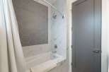 Experience modern luxury in this bathroom, featuring a sleek bathtub surrounded by elegant marble-patterned tiles.