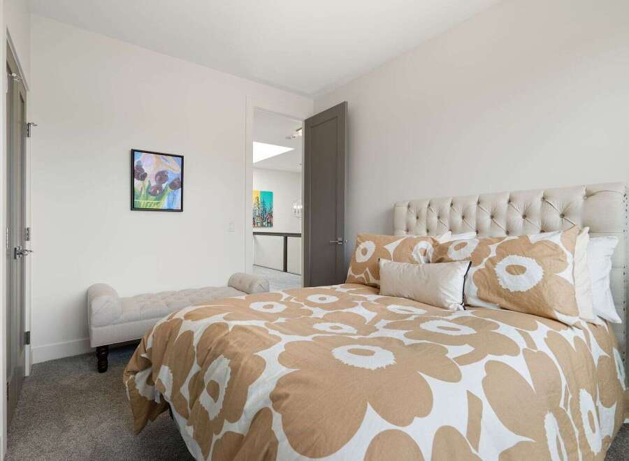 This inviting bedroom features a plush, tufted headboard and a stylish duvet with a large floral pattern.