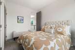This inviting bedroom features a plush, tufted headboard and a stylish duvet with a large floral pattern.