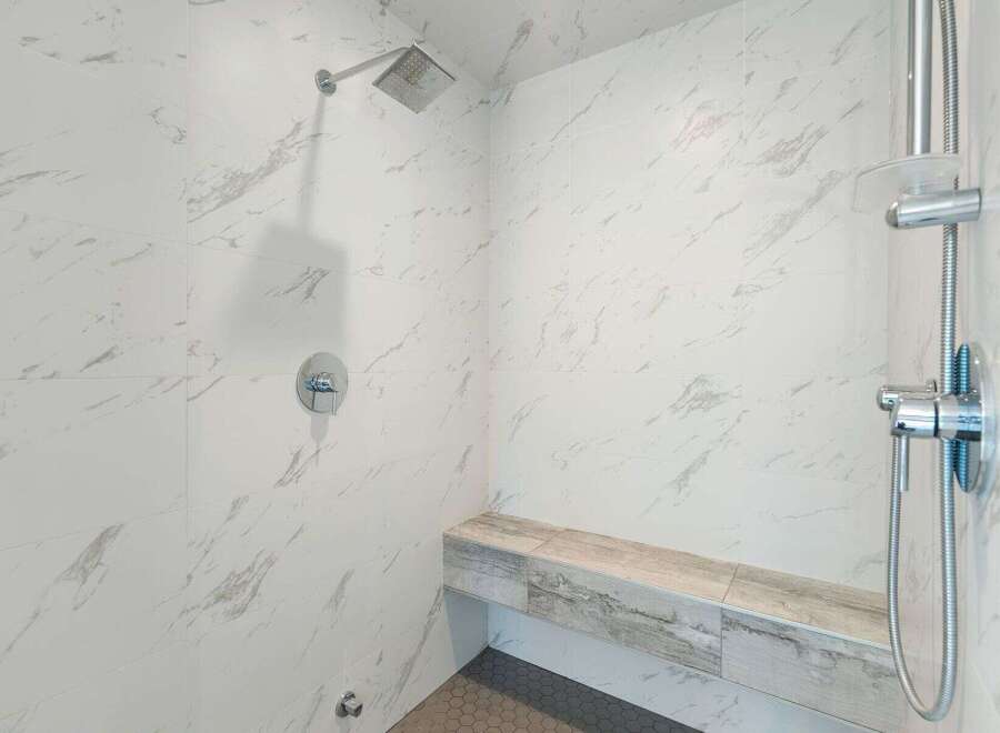 Experience modern luxury in this stunning shower featuring elegant marble-look tiles and a built-in bench for ultimate comfort.
