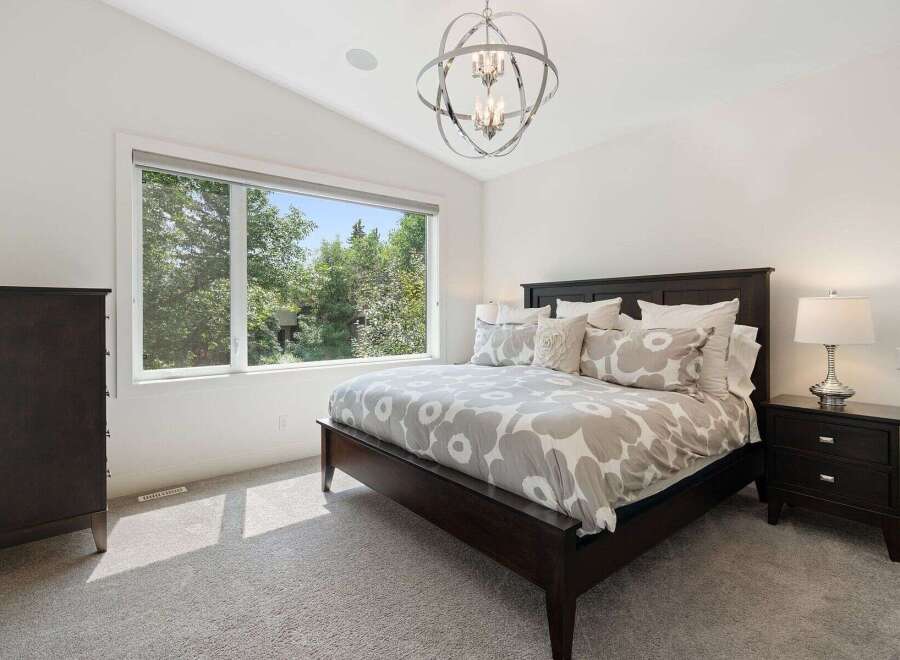 Experience serene living in this beautifully appointed bedroom, featuring a large window that floods the space with natural light and offers picturesque views of lush greenery.