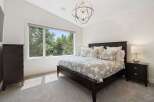 Experience serene living in this beautifully appointed bedroom, featuring a large window that floods the space with natural light and offers picturesque views of lush greenery.