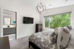 Experience modern comfort in this beautifully appointed bedroom, featuring a large window with lush green views and a stylish geometric chandelier.