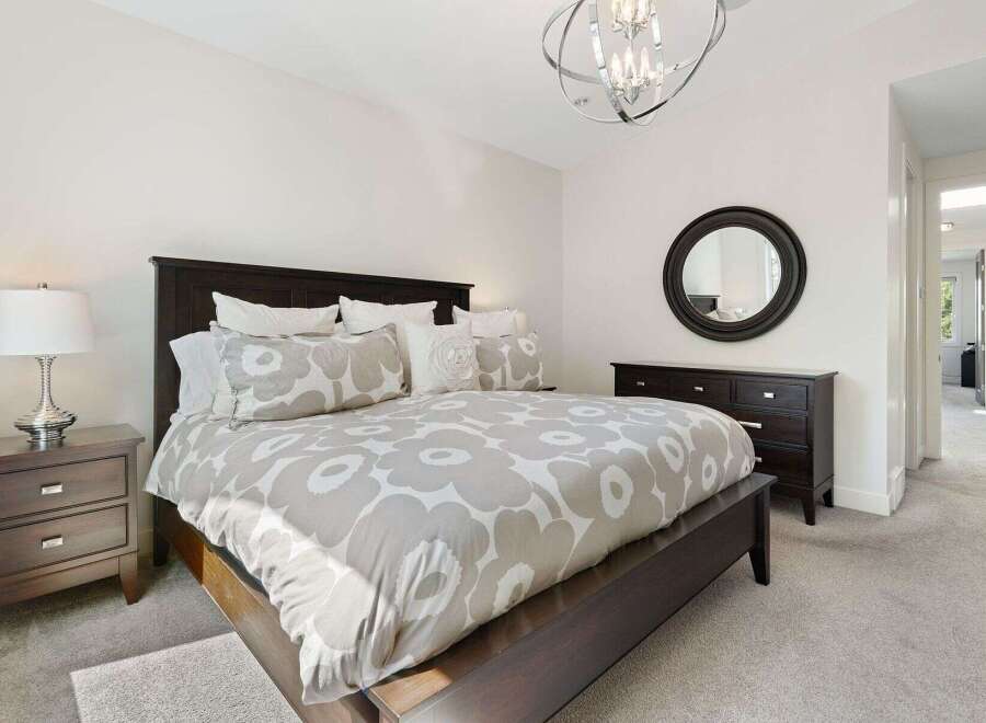 This inviting bedroom features a spacious dark wood bed adorned with a stylish floral duvet and plush pillows.