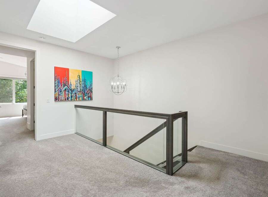 Experience modern luxury in this stunning home featuring a bright and airy upper hallway with a large skylight.