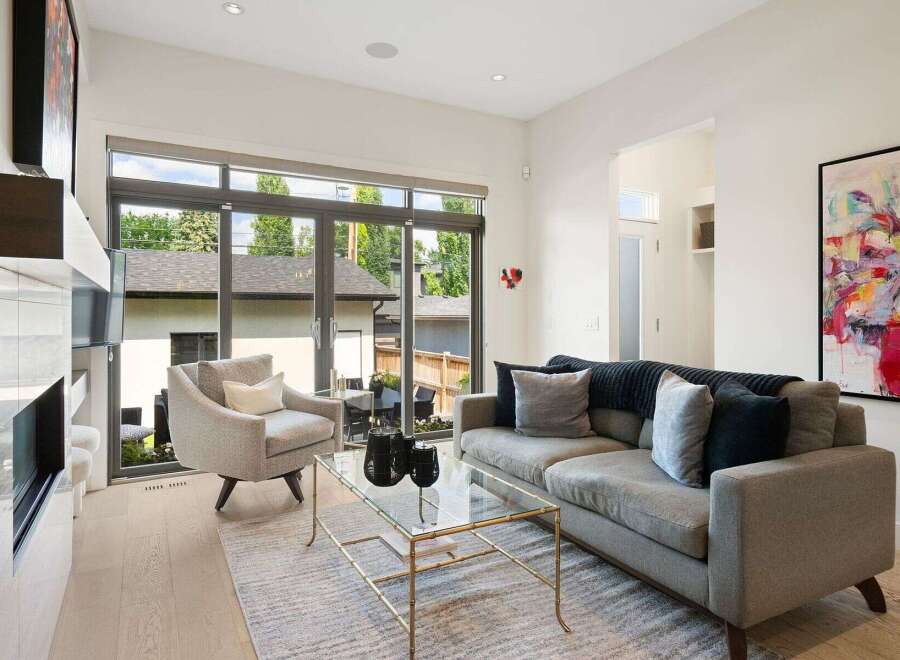 Experience modern living in this bright and airy living room, featuring a sleek fireplace and expansive windows that flood the space with natural light.