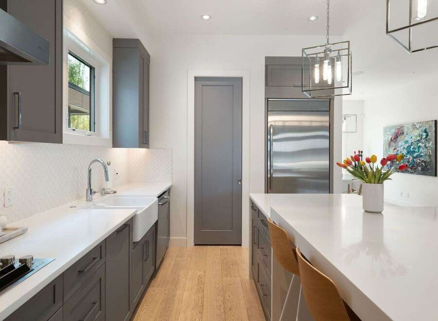 Experience modern luxury in this stunning kitchen, featuring sleek grey cabinetry, a farmhouse sink, and a spacious quartz island perfect for entertaining.