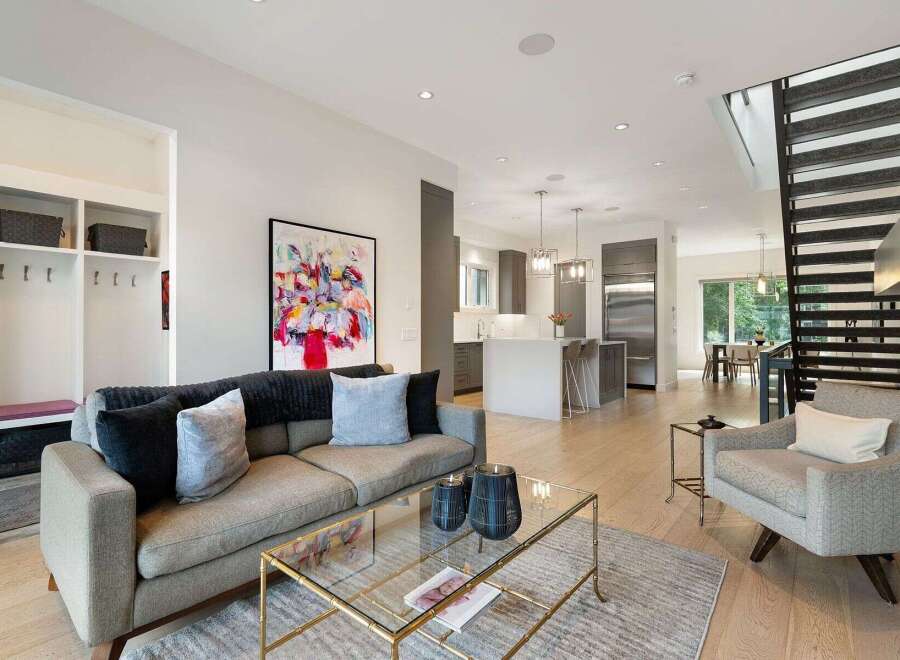 Experience modern living in this stunning open-concept home, featuring a spacious living area with a vibrant abstract artwork and comfortable seating.