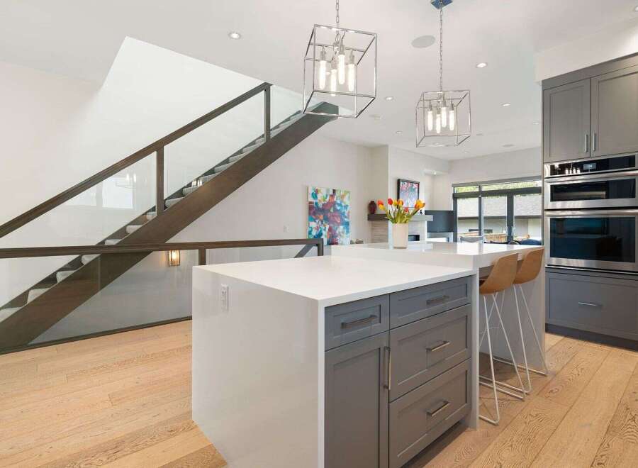 Experience modern luxury in this stunning kitchen featuring sleek gray cabinetry, a spacious quartz island, and high-end stainless steel appliances.