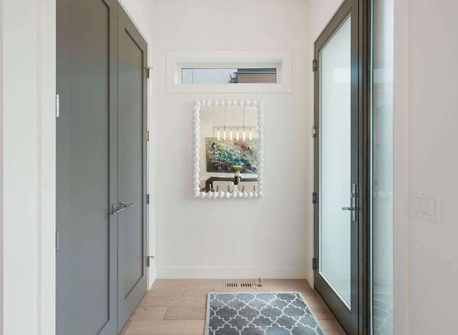 Step into this elegant entryway featuring a sleek grey double door closet and a modern glass door leading outside.