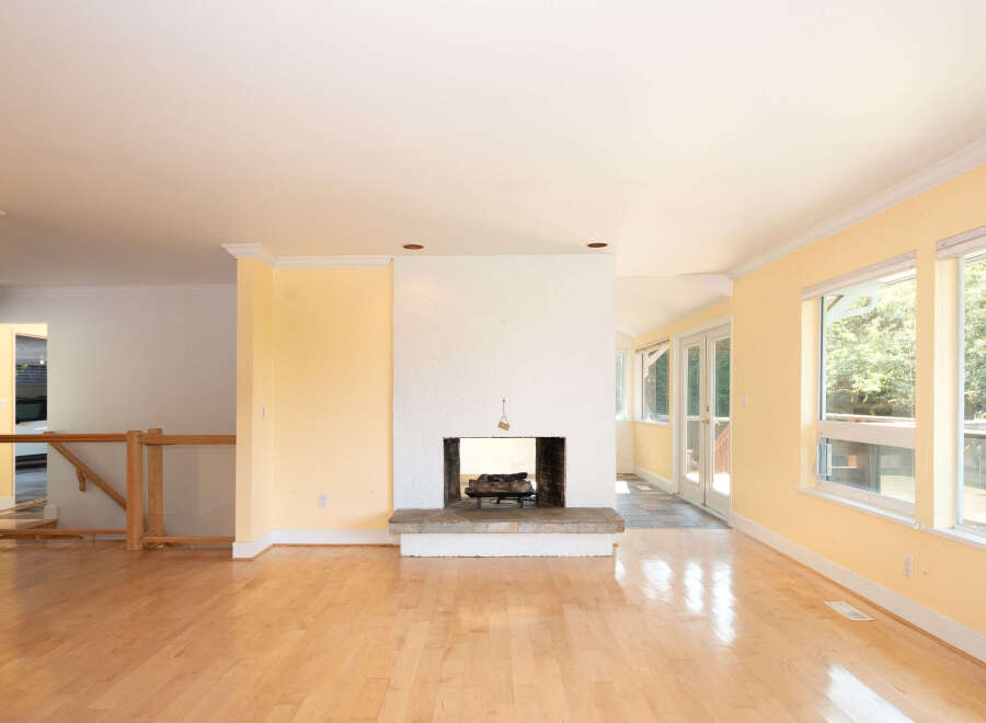 Step into this bright and airy living space featuring gleaming hardwood floors and a charming stone fireplace, perfect for cozy evenings.