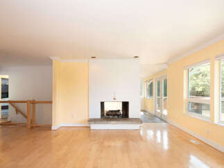 Step into this bright and airy living space featuring gleaming hardwood floors and a charming stone fireplace, perfect for cozy evenings.