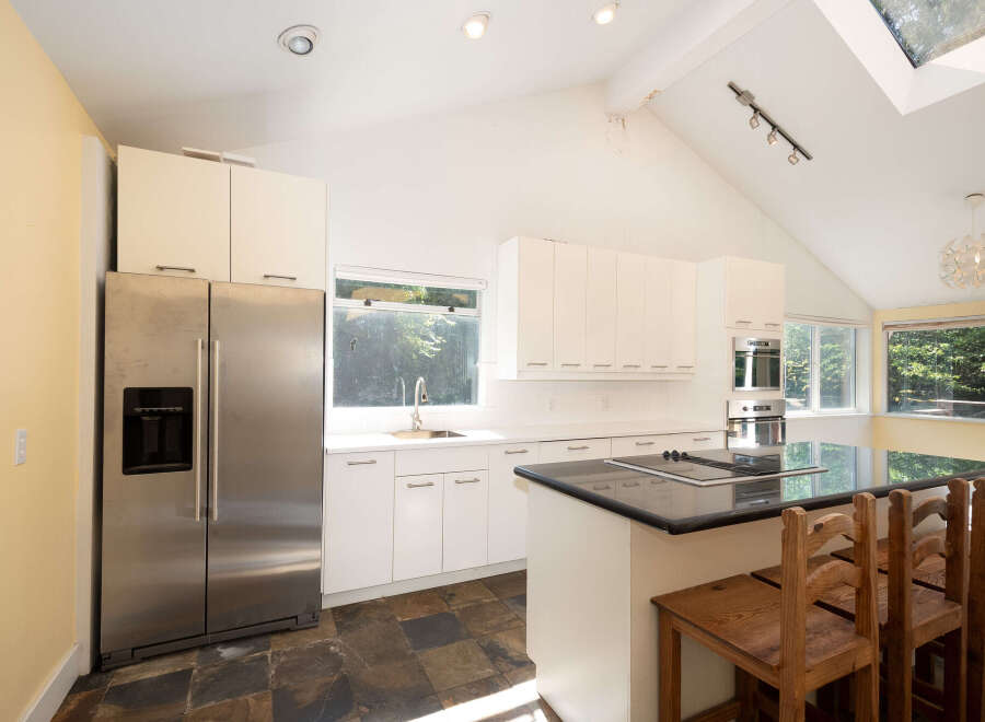 This modern kitchen boasts sleek white cabinetry and a spacious island with a built-in stovetop, perfect for culinary enthusiasts.