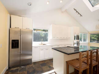This modern kitchen boasts sleek white cabinetry and a spacious island with a built-in stovetop, perfect for culinary enthusiasts.