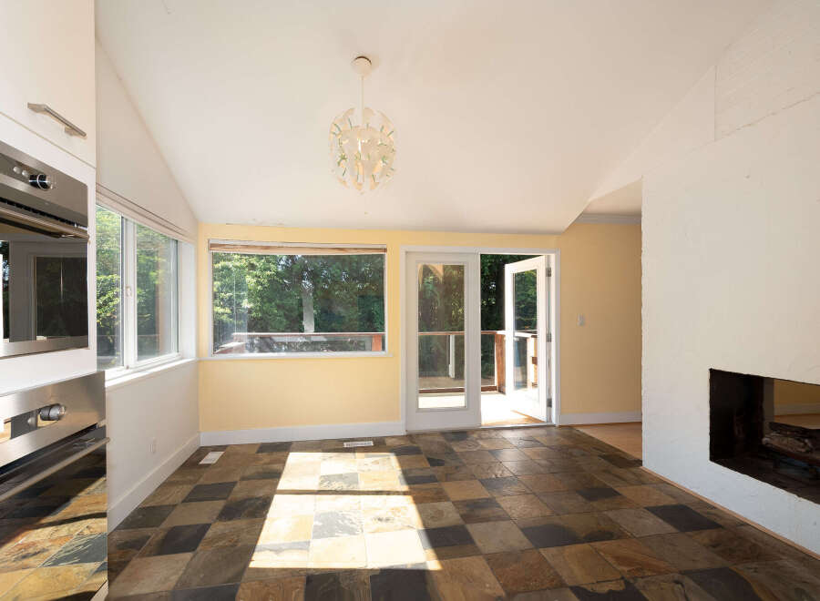 This sun-drenched room features a unique slate tile floor and a large picture window offering views of lush greenery.