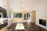 This sun-drenched room features a unique slate tile floor and a large picture window offering views of lush greenery.