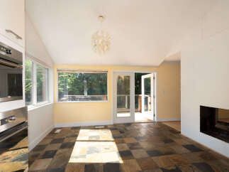 This sun-drenched room features a unique slate tile floor and a large picture window offering views of lush greenery.