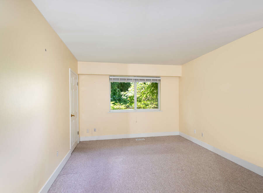 This spacious room features a large window offering abundant natural light and views of lush greenery.