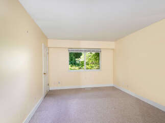 This spacious room features a large window offering abundant natural light and views of lush greenery.