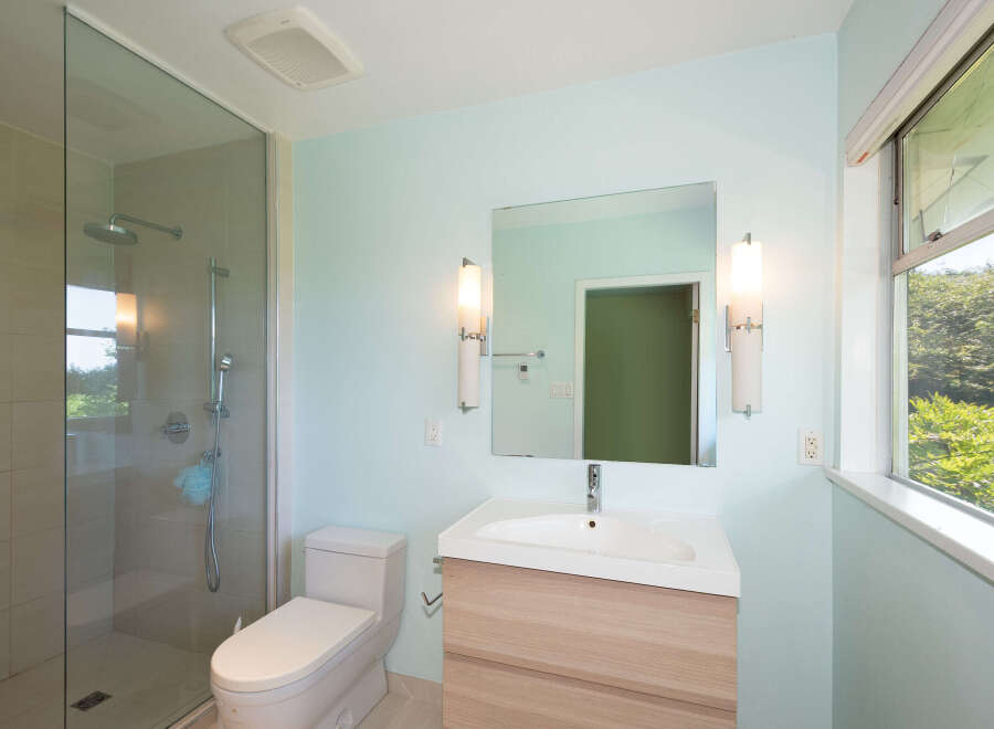 This modern bathroom features a spacious glass-enclosed shower with a rainfall showerhead and a handheld wand.