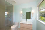 This modern bathroom features a spacious glass-enclosed shower with a rainfall showerhead and a handheld wand.