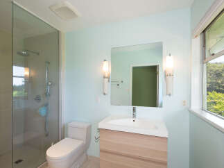 This modern bathroom features a spacious glass-enclosed shower with a rainfall showerhead and a handheld wand.