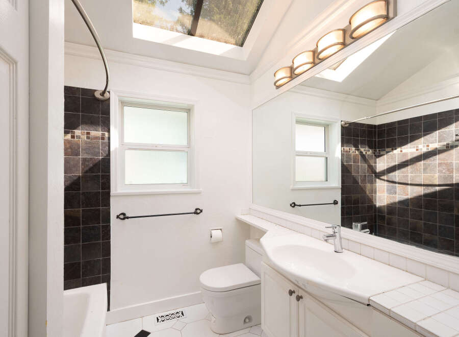 This bright bathroom features a skylight and a large vanity mirror, creating an airy and spacious feel.
