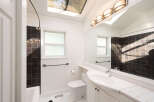 This bright bathroom features a skylight and a large vanity mirror, creating an airy and spacious feel.