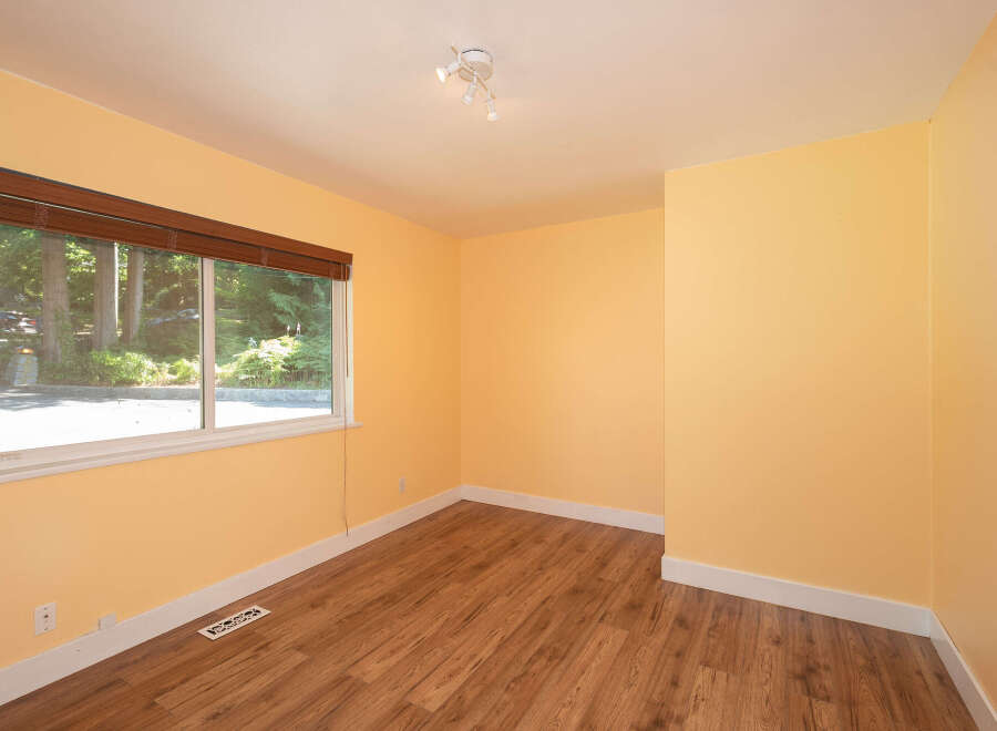 This empty room features warm yellow walls and a beautiful wood-look laminate floor, creating a bright and inviting atmosphere.